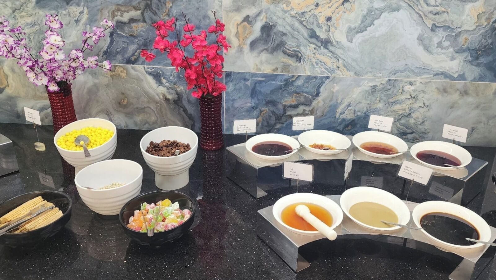 A buffet with various food items and a decorative vase with flowers.