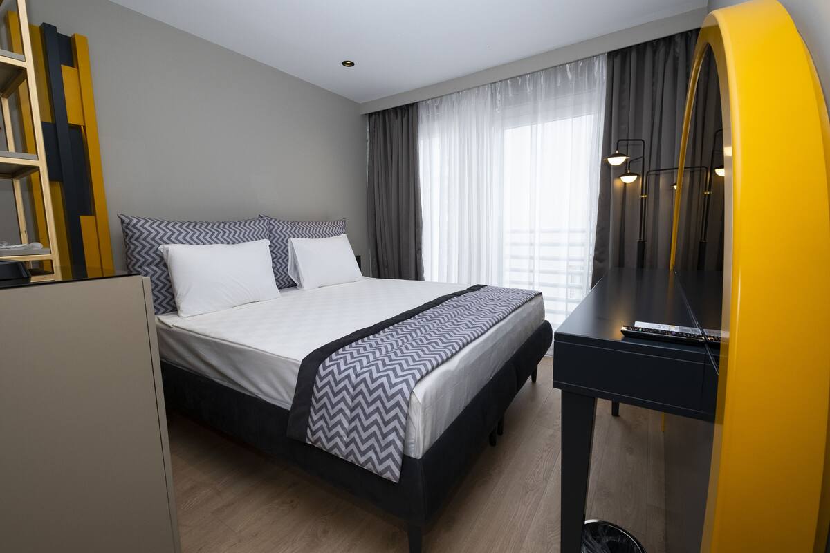 A hotel room with a bed, a desk, and a wardrobe.
