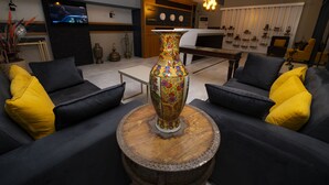 A modern living room with a large decorative vase on a wooden table, black sofas with yellow cushions, and a television mounted on the wall. - Sea City Devran Hotel & Spa (Konyaalti)