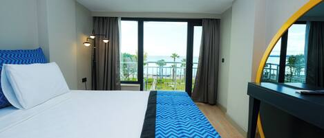 Une chambre d’hôtel avec un lit, un bureau et une vue sur la mer.