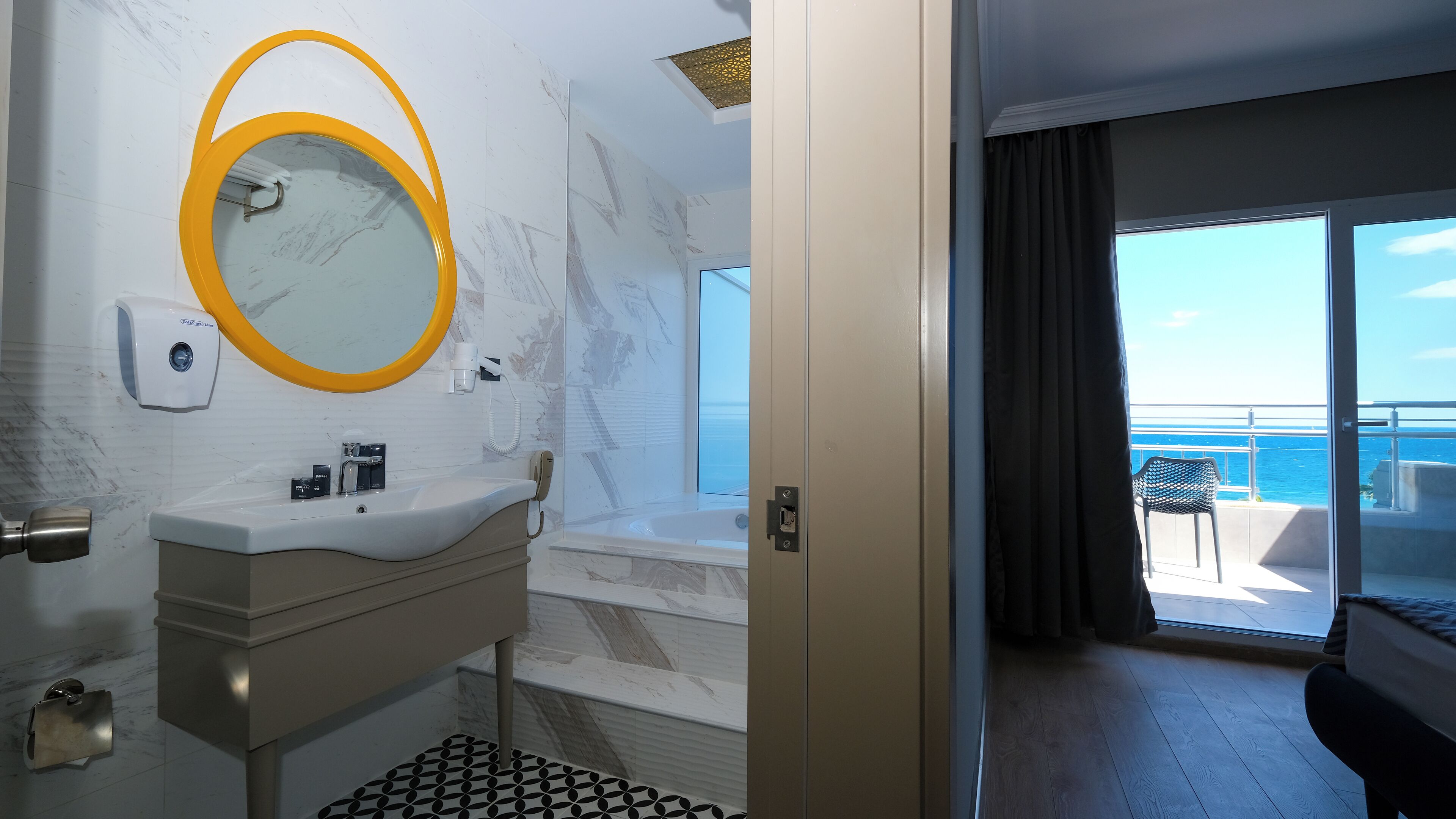 A modern bathroom with a marble sink, a yellow-framed mirror, and a handheld showerhead.