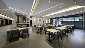 A modern dining area with multiple tables and chairs, a marble countertop, and a large window providing a view of the outside.