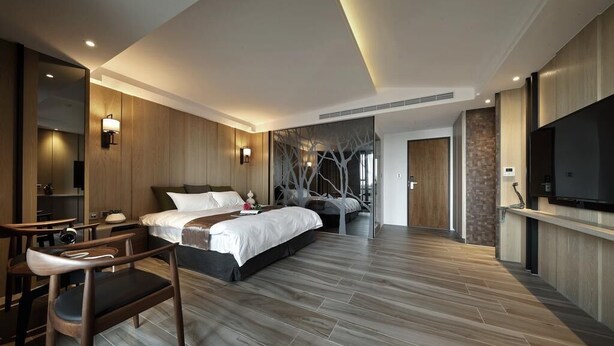 A modern hotel room with a large bed, a desk, and a television.
