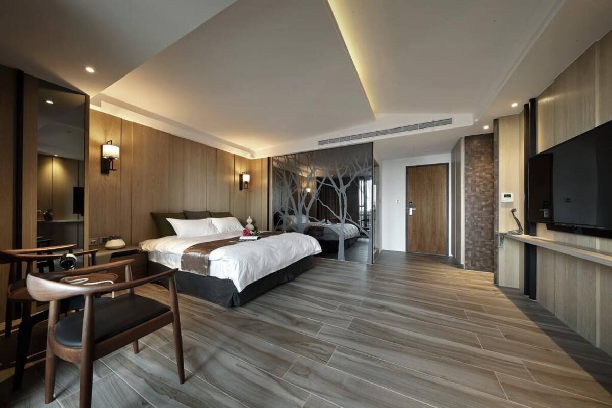 A modern hotel room with a large bed, a desk, and a television.