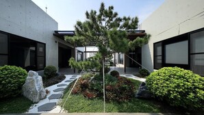 A modern building with a central courtyard featuring a tree, rock garden, and well-maintained shrubs.