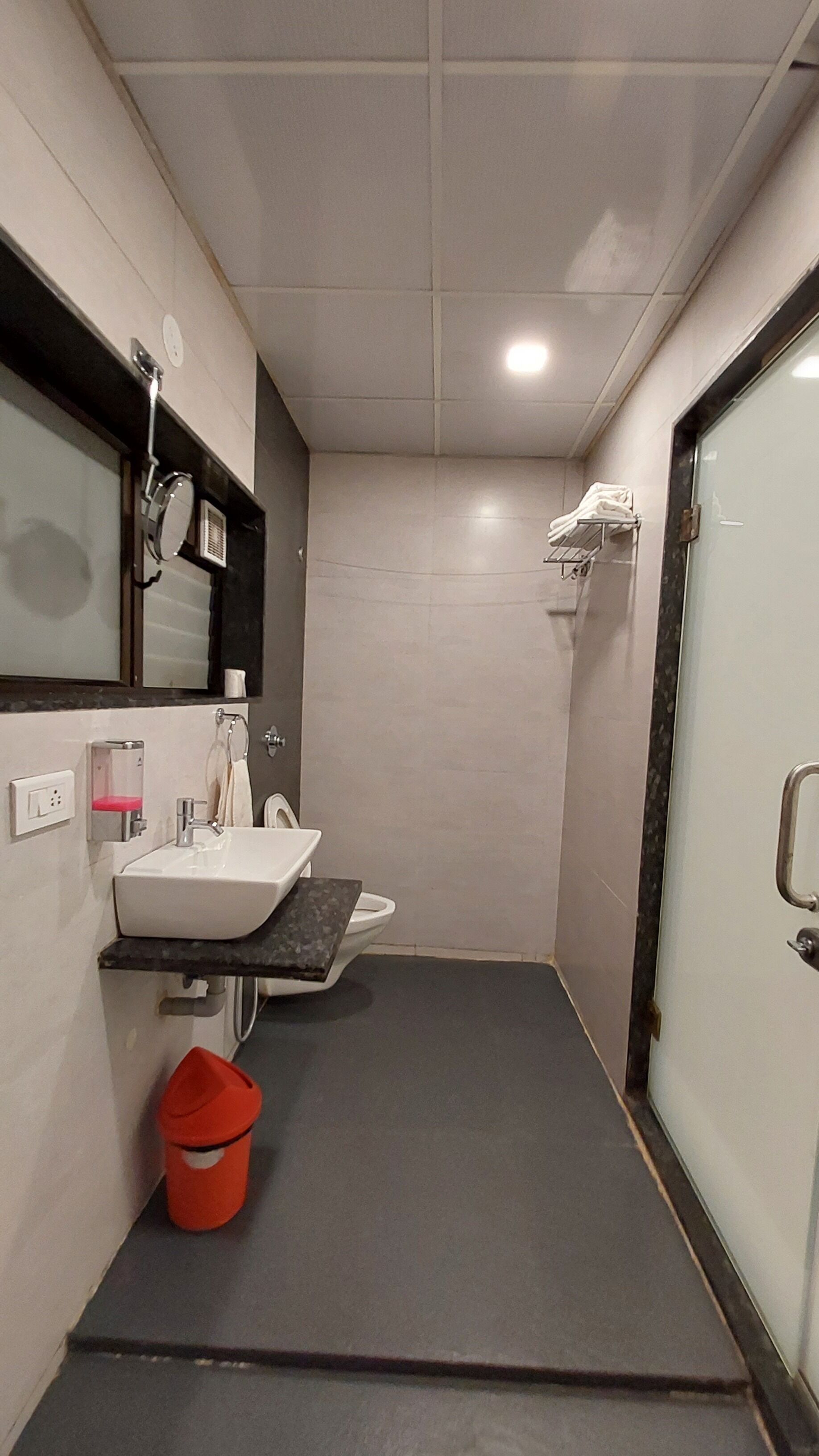 Ein kleines Badezimmer mit einem weißen Waschbecken, einem Spiegel, einem Handtuchhalter und einer Toilette.