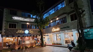Un edificio con varios locales comerciales en la planta baja, incluyendo una cafetería y un restaurante.