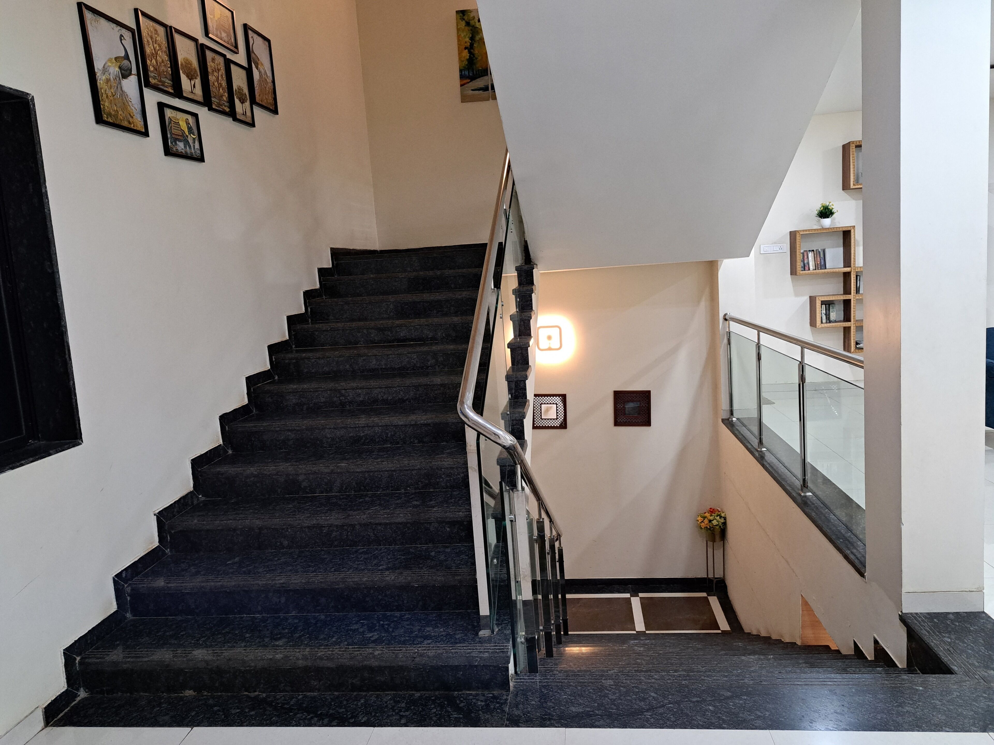 A staircase with dark steps, a handrail, and a wall with framed pictures.