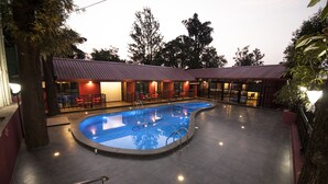 Una piscina con un edificio de techo rojo al fondo.