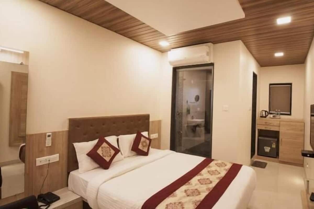 Una habitación de hotel con cama, mesita de noche, televisión y espejo.