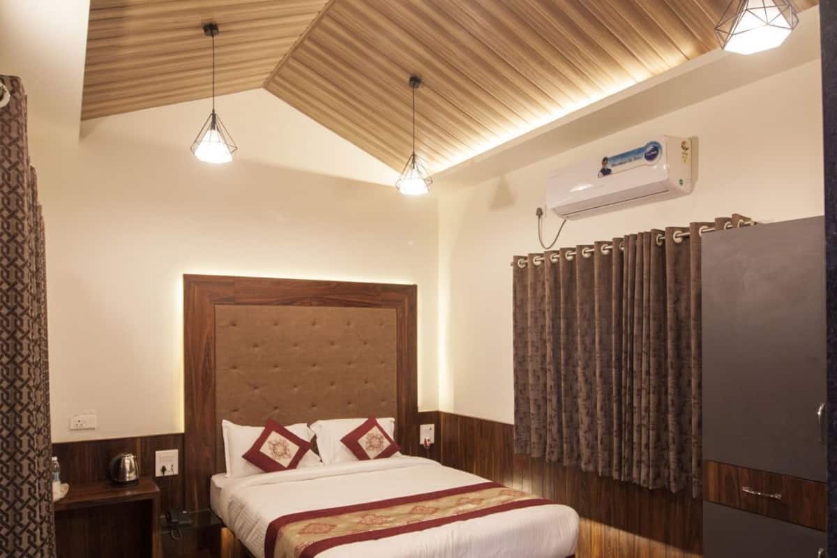 Un dormitorio con techo de madera, una cama con cabecera, una mesita de noche, un armario y un aire acondicionado instalado en la pared.
