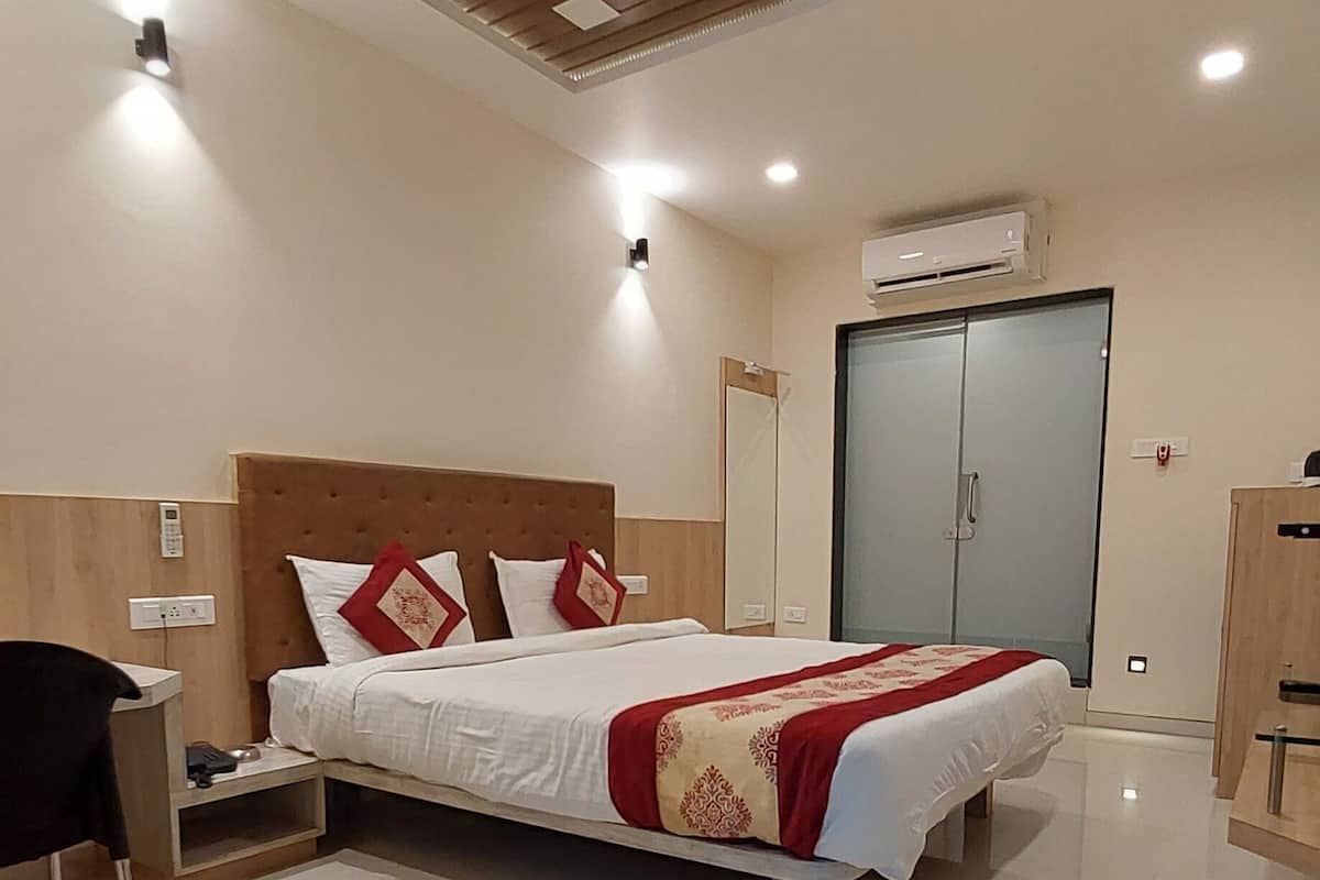 Una habitación de hotel moderna con una cama grande, mesitas de noche, un armario y un equipo de aire acondicionado.