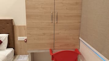 Un dormitorio con un armario de madera, una cama con cabecera, una silla roja y una mesita con un menú.
