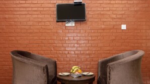 A brick wall with a flat-screen TV mounted above a table with two chairs. - Hotel Marigold (Mahamanjushree Nagarkot)