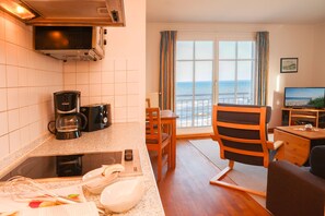 Un espacio habitable compacto con kitchenette, zona de comedor y vista al mar.