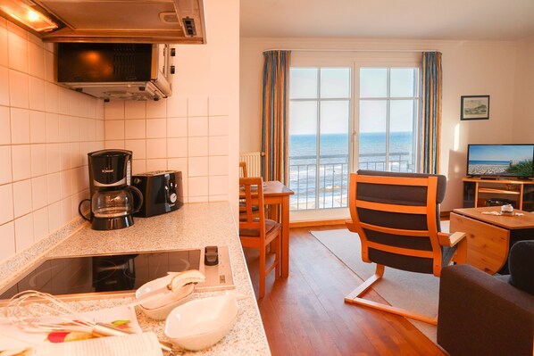 Un espacio habitable compacto con kitchenette, zona de comedor y vista al mar.