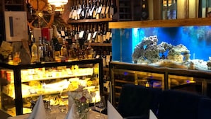 Un restaurant doté d’un bar, d’un grand aquarium et de tables aménagées pour le service.