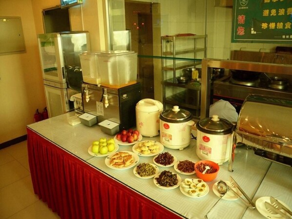 A buffet setup with various food items, a coffee station, and a microwave.
