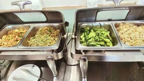 A buffet with various dishes including noodles, vegetables, and fried rice.