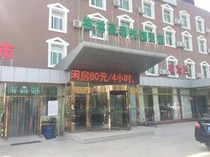 A hotel with a sign indicating room rates and a storefront with a sign for a department.