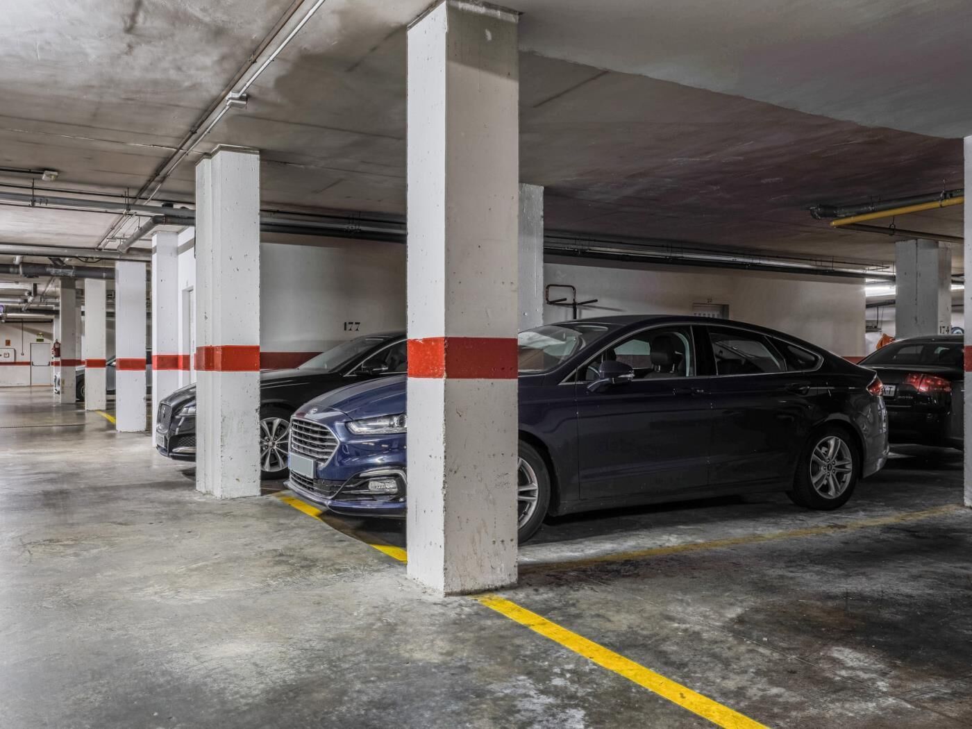 Uma garagem de estacionamento em vários níveis, com pilares de concreto e linhas de estacionamento amarelas.