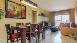 Una sala de estar moderna con comedor, televisor y balcón con vistas.