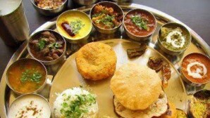 A traditional Indian meal served on a metal plate with various dishes including rice, bread, and multiple curries. - Hotel Bharat Palace (Jaipur)