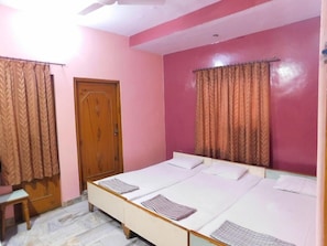 A bedroom with pink walls, a wooden door, and a bed with striped bedding. - Hotel Bharat Palace (Jaipur)