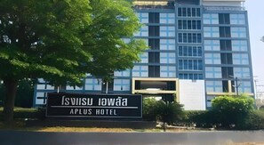 Señal de APLUS HOTEL con un edificio moderno al fondo.
