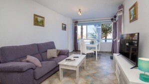 A living room with a purple sofa, a white coffee table, a TV on a white cabinet, and a dining area with a white table and chairs. - Rocamar by Interhome (Calpe/Calp)