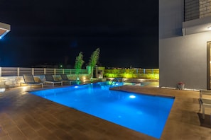 Relax by the pool surrounded by palm trees and lounge chairs.