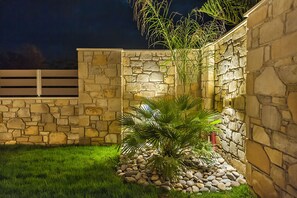 Relax on a bench amidst a serene garden setting with a beautifully manicured lawn.