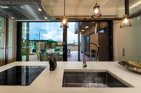 Enjoy cooking in this well-equipped kitchen with a sleek induction cooktop and stainless steel sink, offering a view of the city.