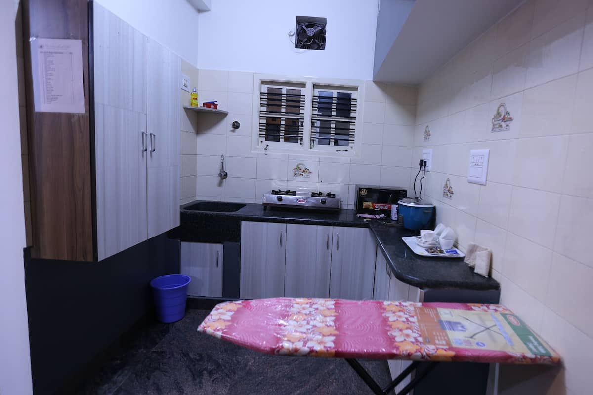 Una cocina compacta con estufa a gas, pileta y un pequeño ventanal con persianas.