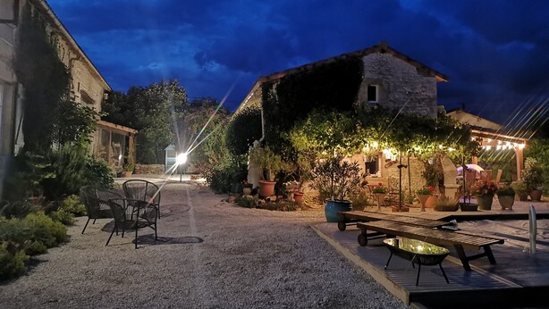 An outdoor patio area with a gravel surface, wooden furniture, and potted plants. - Luxurious private gite with pool, terrace, large gardens, golf simulator and gym (Limalonges)