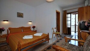Une chambre à coucher avec un lit en bois, une chaise, un téléviseur et une porte donnant sur un balcon.