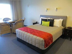 Una habitación de hotel con una cama, un escritorio y dos sillas.