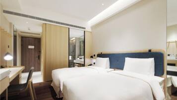 A hotel room with a large bed, a desk, a chair, and a mirror.
