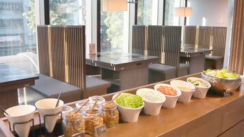 A buffet area with various food options and a view of the city through large windows.
