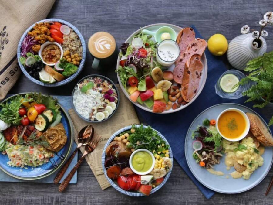 Une variété de plats présentés sur des assiettes, notamment des salades, des soupes et du pain, disposés sur une table en bois.