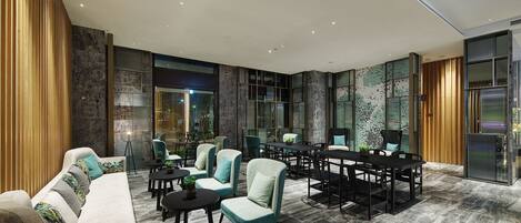 Un espacio lounge moderno con sofá, sillas, una mesa de comedor y una zona de bar.