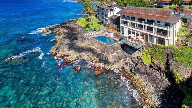 A coastal property with a large house, a swimming pool, and a view of the ocean. - Captivating Ocean Front Condo Living-Poipu Shores (POIPU)