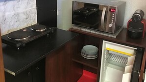 Une petite cuisine équipée comprenant un four à micro-ondes, un petit four, une machine à café et un mini-réfrigérateur.