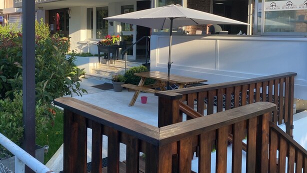 Un hôtel doté d’une terrasse, d’un drapeau et d’une enseigne indiquant « Hôtel de Savoie ».