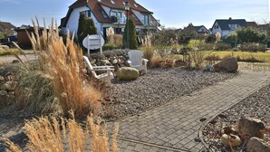 A modern house with a sloped roof, a paved driveway, and a garden with rocks and dry plants.