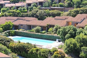 A residential area with multiple houses, a swimming pool, and lush greenery.