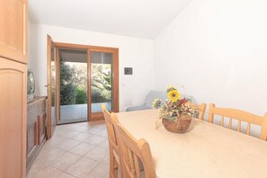 A dining area with a table set for two, a wooden chair, and a vase of flowers.