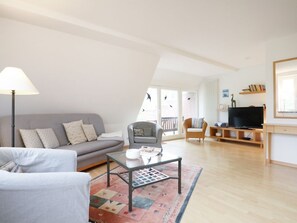 A modern living room with a sofa, armchair, coffee table, and a TV stand. - Beach view, Germany (Ostseebad Boltenhagen)