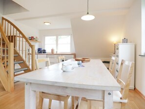 A modern kitchen with a wooden staircase, white cabinets, and a dining table with chairs. - Beach view, Germany (Ostseebad Boltenhagen)