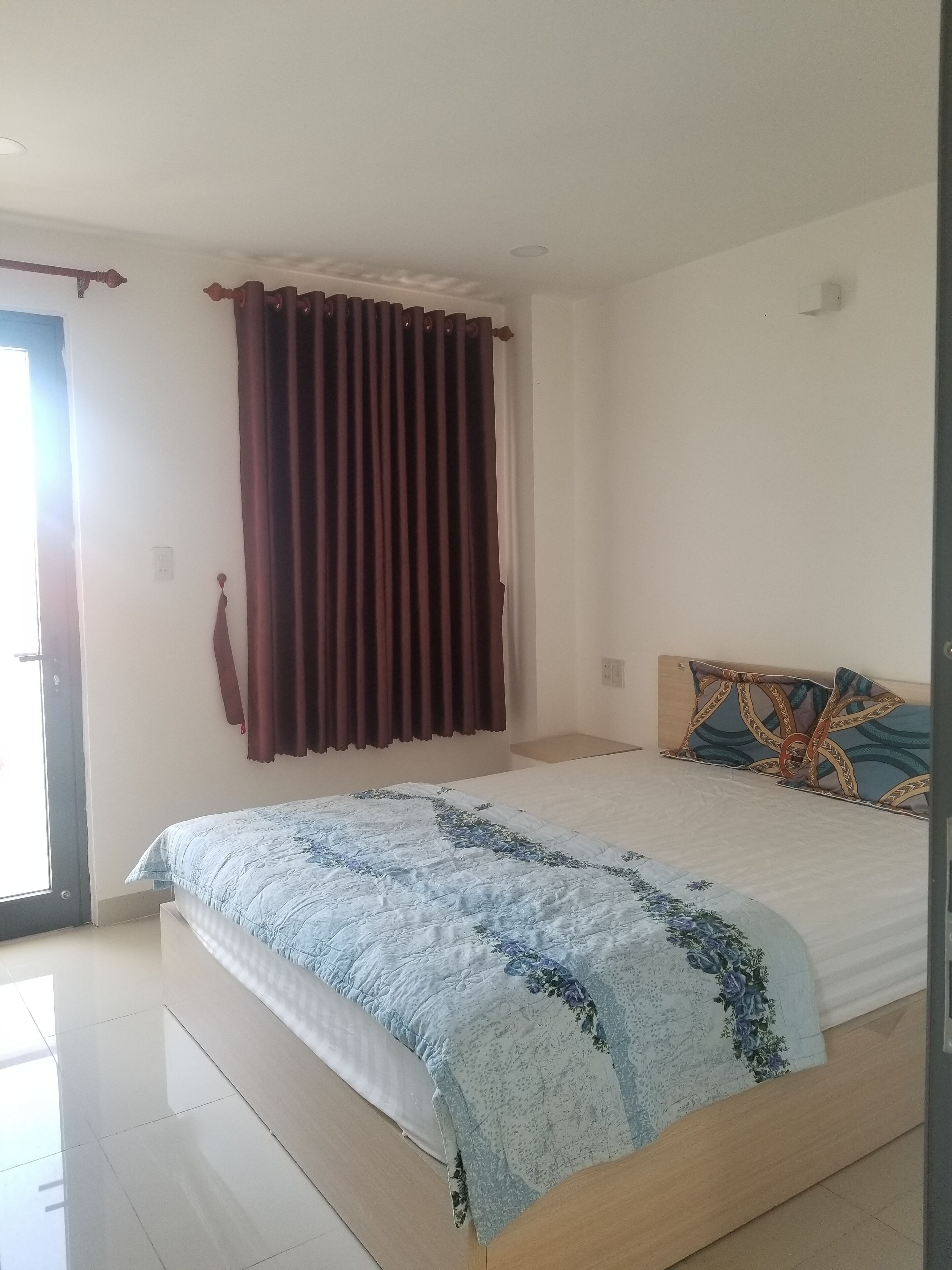 Um quarto com cama, cortinas e cabeceira.